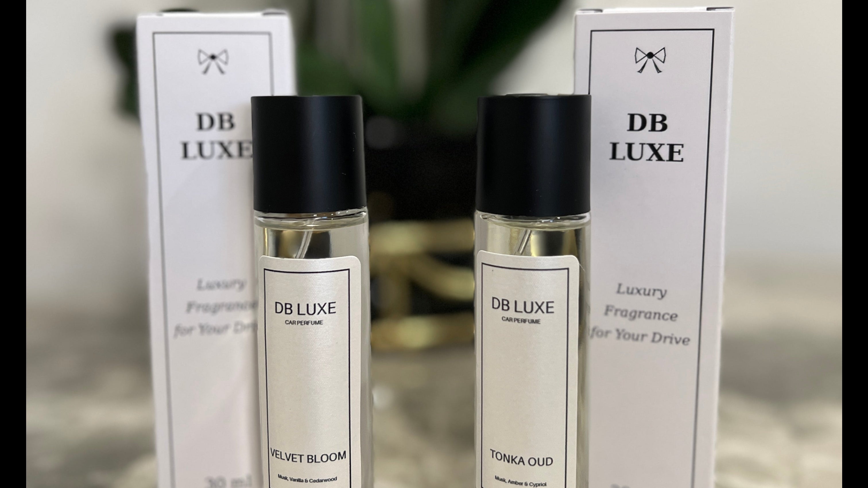 Two DB Luxe perfume bottles with black caps on a marble surface.